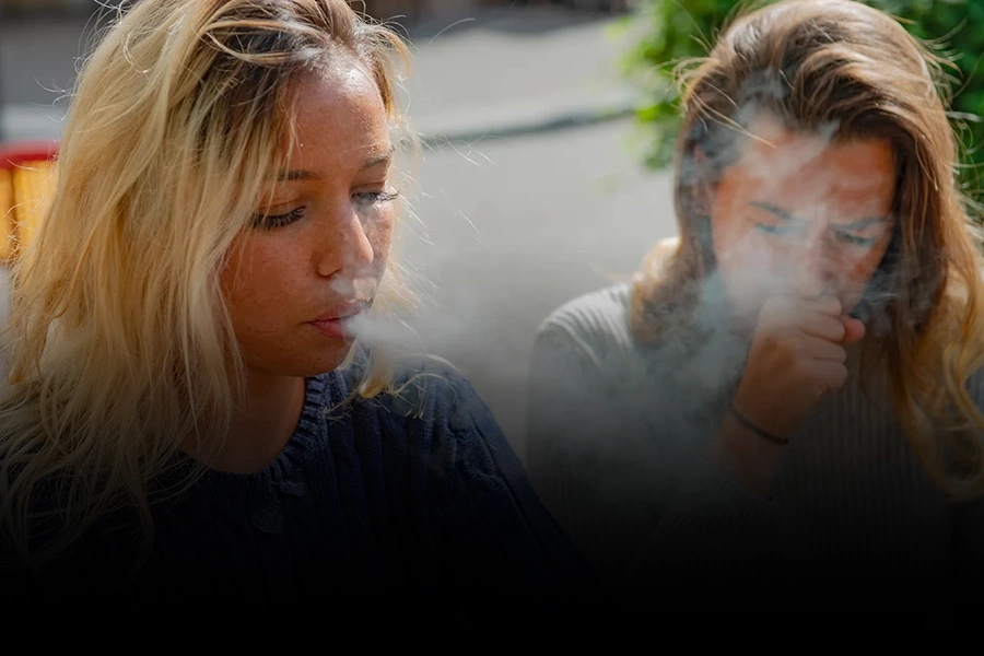 Two women smoking outdoors, illustrating the harmful connection between smoking and asthma triggers