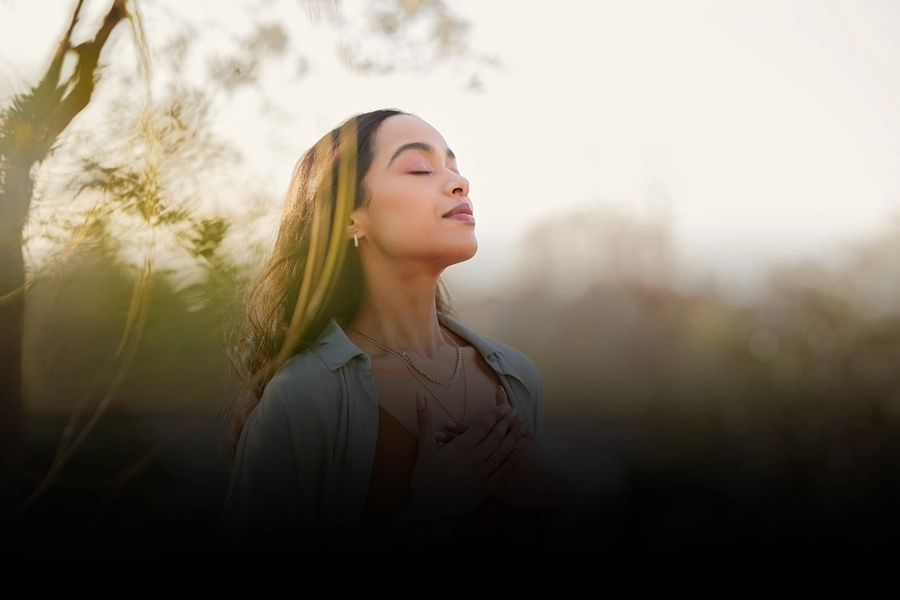 Woman meditating outdoors to enhance mental focus and inner calm through mindfulness and stress-relief practices.